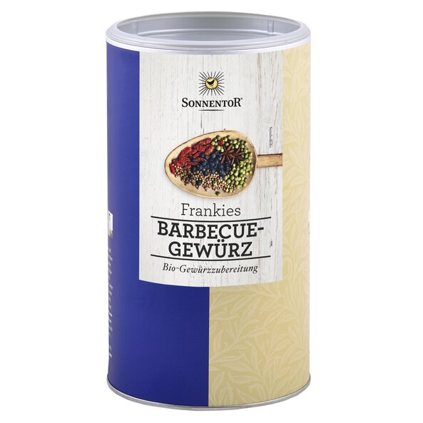 A photo of a big jumbo spice tin Frankies Barbecue Spice Mix. On it is a wooden spoon with colorful spices.