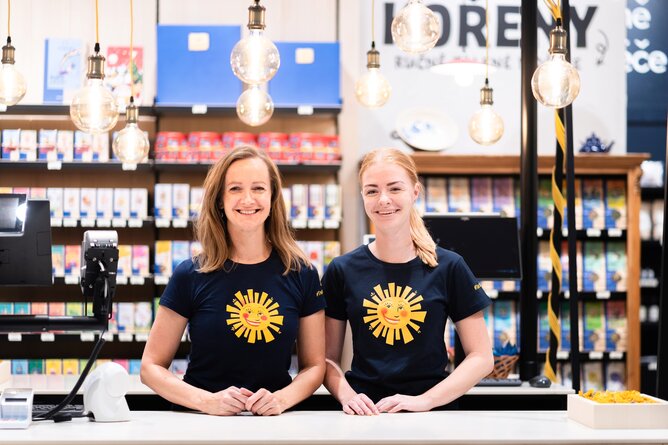 Na fotografii jsou dvě usmívající se prodavačky za pokladnou moderně a pestře působící prodejny SONNENTOR. | © SONNENTOR