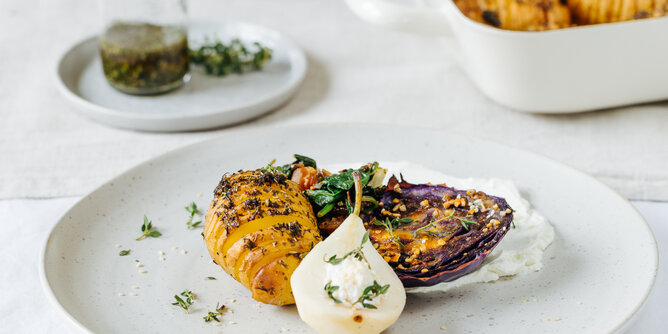 Rotkohl Steaks auf Ziegen Frischkäse mit Dattel-Pilz-Spinat und Fächerkartoffeln | © SONNENTOR Auf dem Foto sieht man ein Rotkohl Steak und daneben Fächerkartoffeln. Auch eine Birne ist zu sehen. | © SONNENTOR